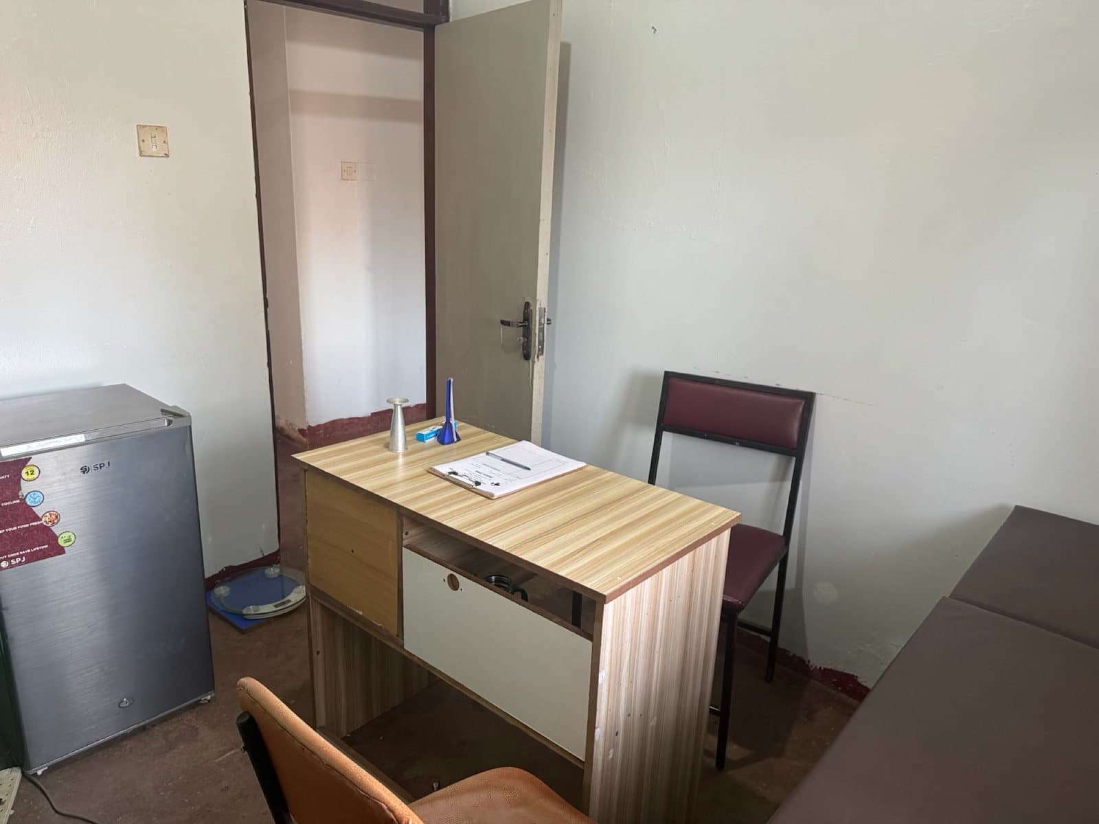 The doctor's room at Shalom Clinic, with a desk, chairs, a fridge, a scale and an examination bed