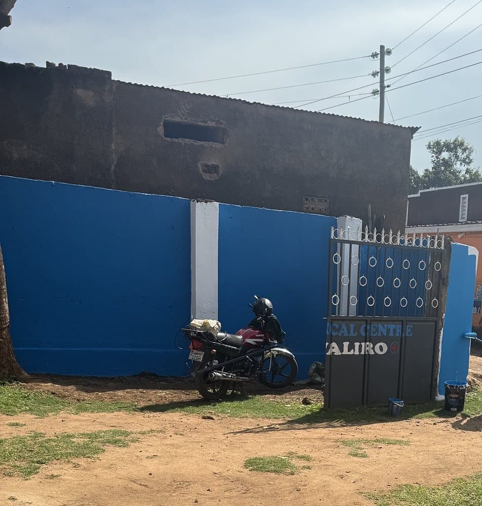 The blue and white compound wall, the gate and a parked motorcycle at Shalom Clinic